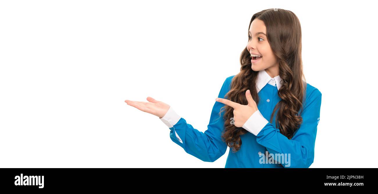 stupito bambino lungo capelli ricci presentando prodotto e puntando il dito sullo spazio di copia, pubblicità. Faccia del bambino, manifesto orizzontale, ragazza adolescente Foto Stock