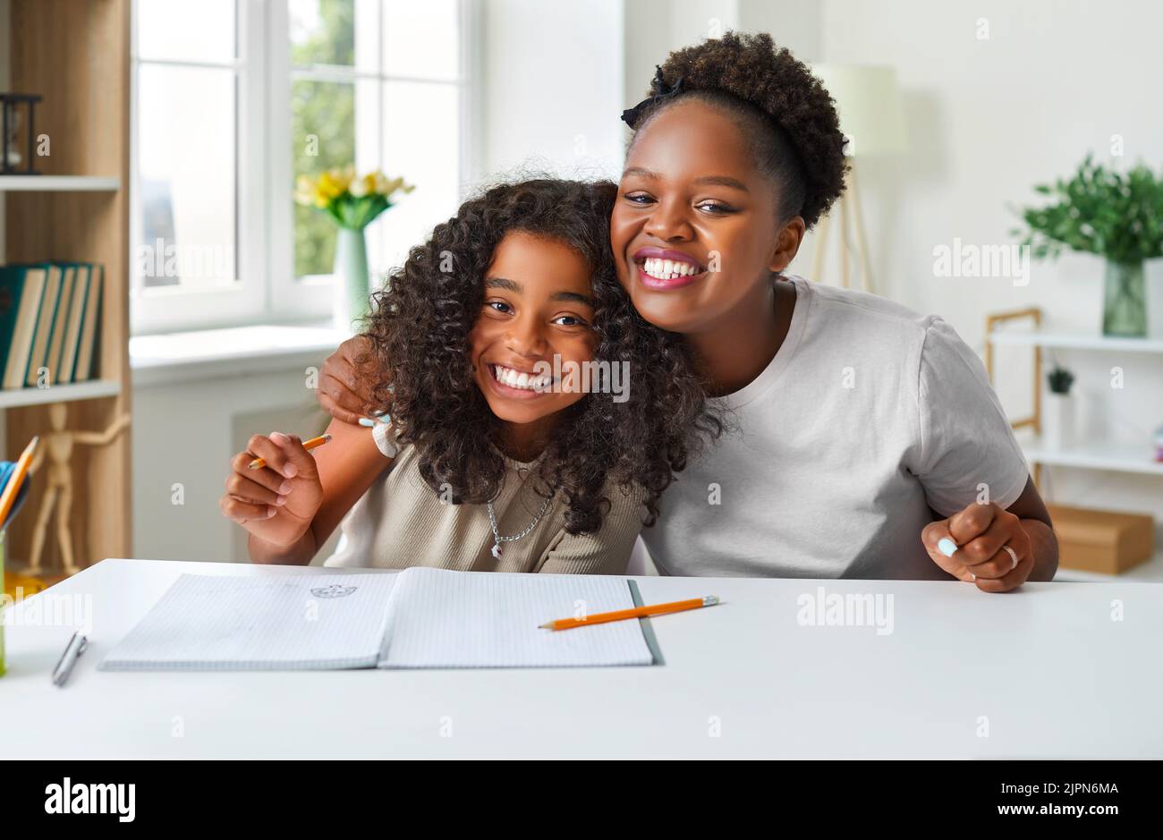 Felice afroamericana madre e figlia che si divertono mentre fanno i compiti insieme Foto Stock