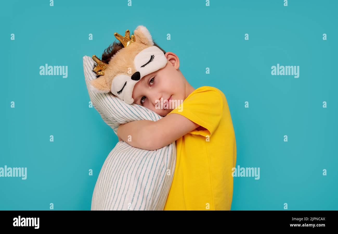 un ragazzo in pigiama che abbraccia un cuscino. Striscione con sfondo blu e copia pasta Foto Stock