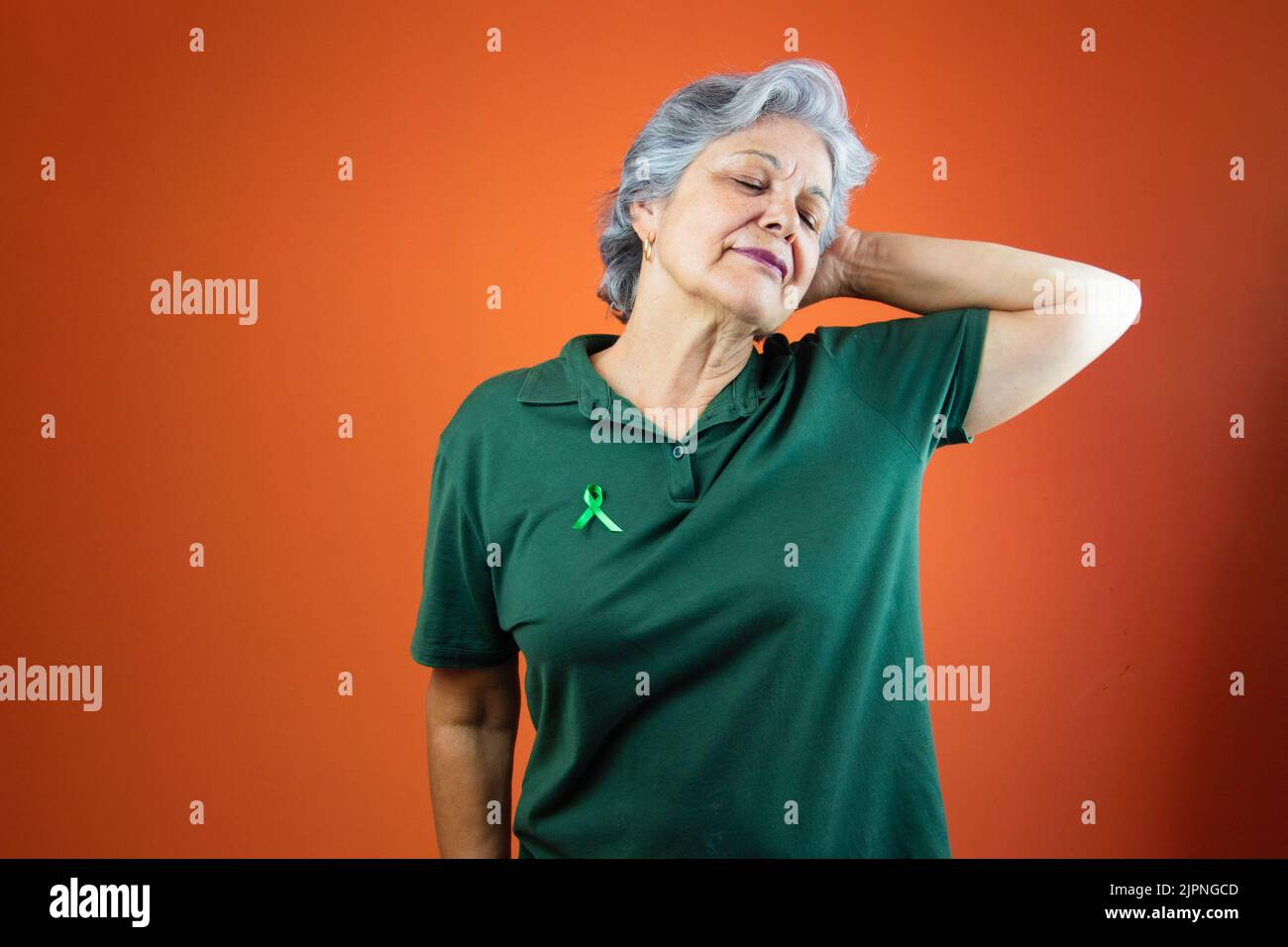 Giornata mondiale della salute mentale - Donna matura con capelli grigi, nastro verde e camicia isolato. Foto Stock