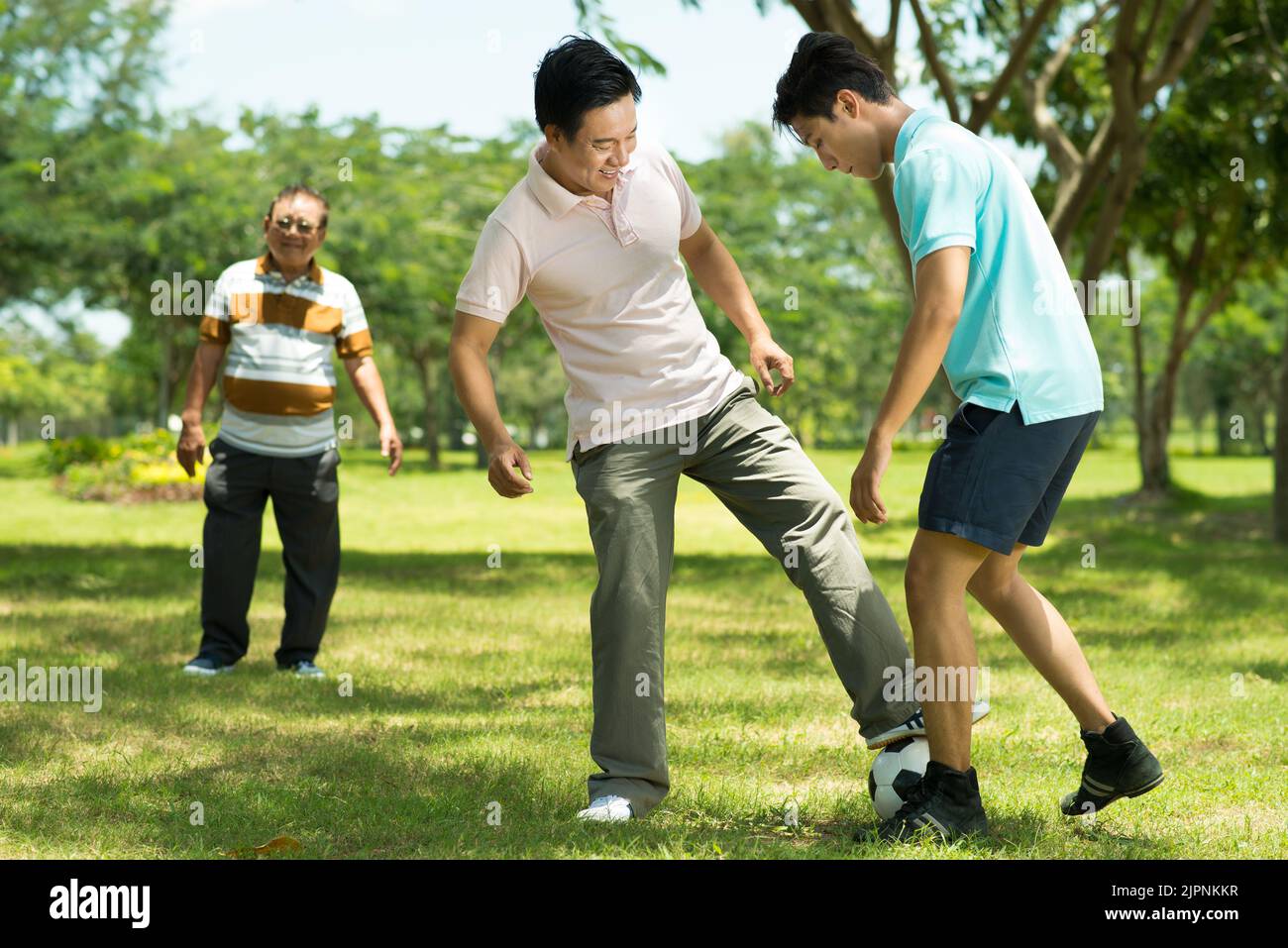 La famiglia vietnamita gioca a calcio nel parco locale Foto Stock