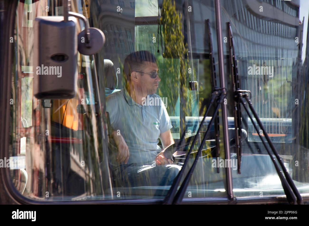 Belgrado-Serbia - 15 giugno 2022: Conducente che guida un autobus urbano, dall'esterno attraverso il parabrezza anteriore con riflessi sul vetro Foto Stock