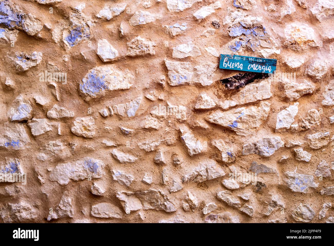 Tessitura di pietra. Muro di pietra naturale. Muro esposto di una vecchia casa e segno con un messaggio positivo. Foto Stock