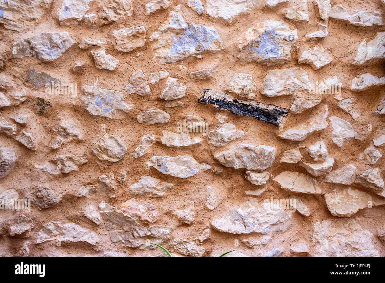 Muro di pietra naturale. Parete esposta di una vecchia casa con un pezzo di Charred. Foto Stock