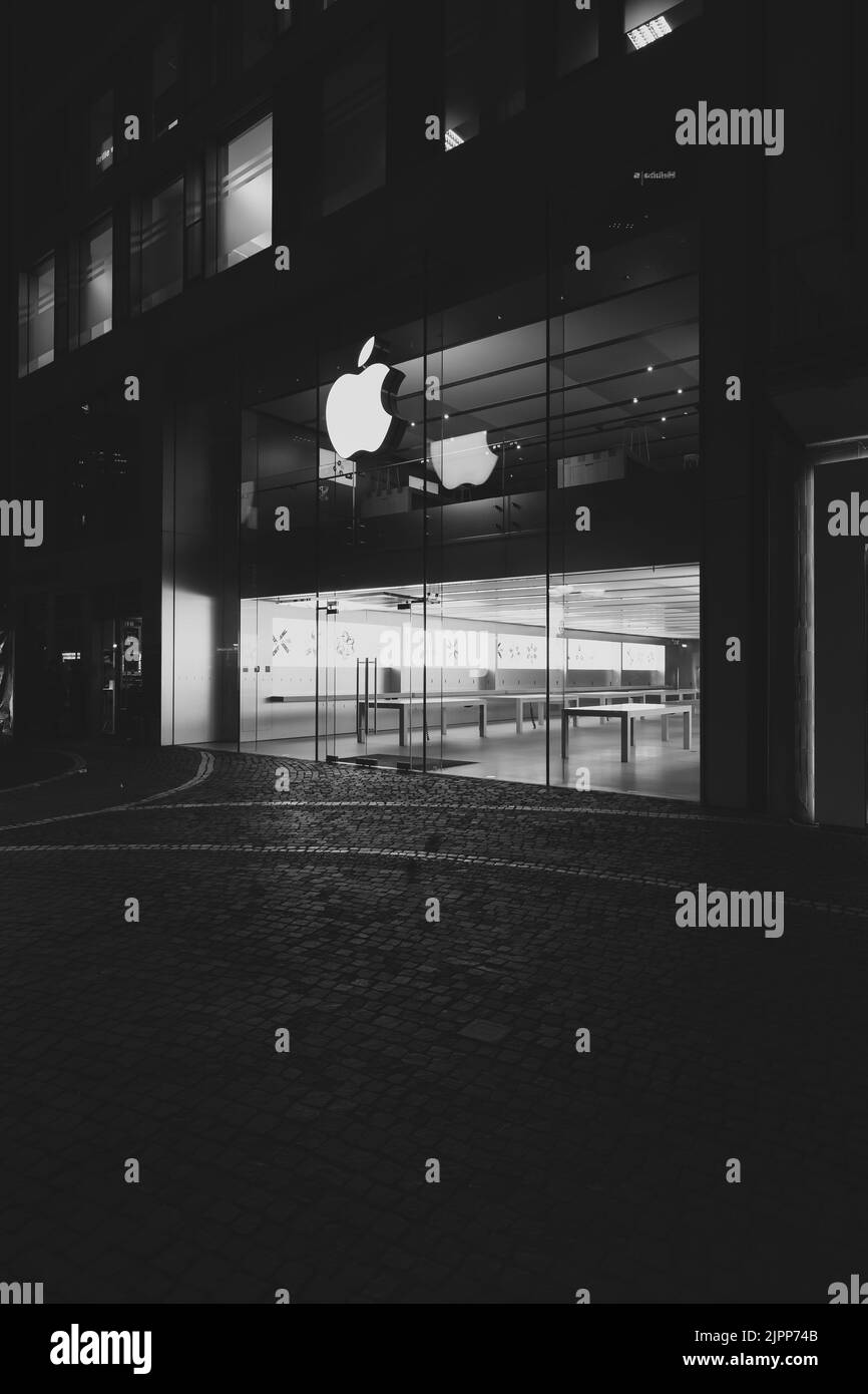 Una foto verticale in scala di grigi della facciata dell'Apple Store illuminata di notte Foto Stock