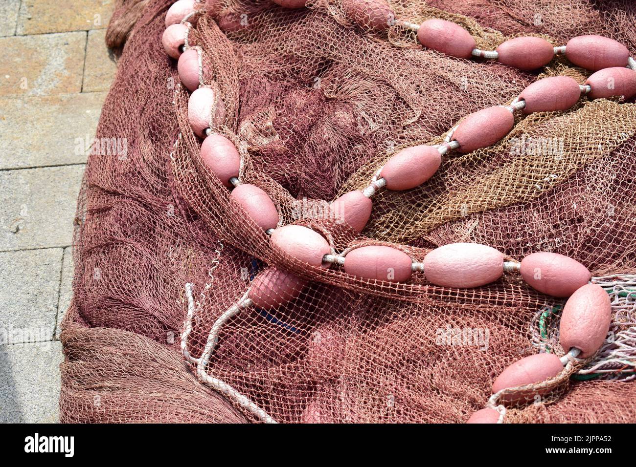 Chiudere la vecchia rete da pesca rossastra con piccole boe. Foto Stock