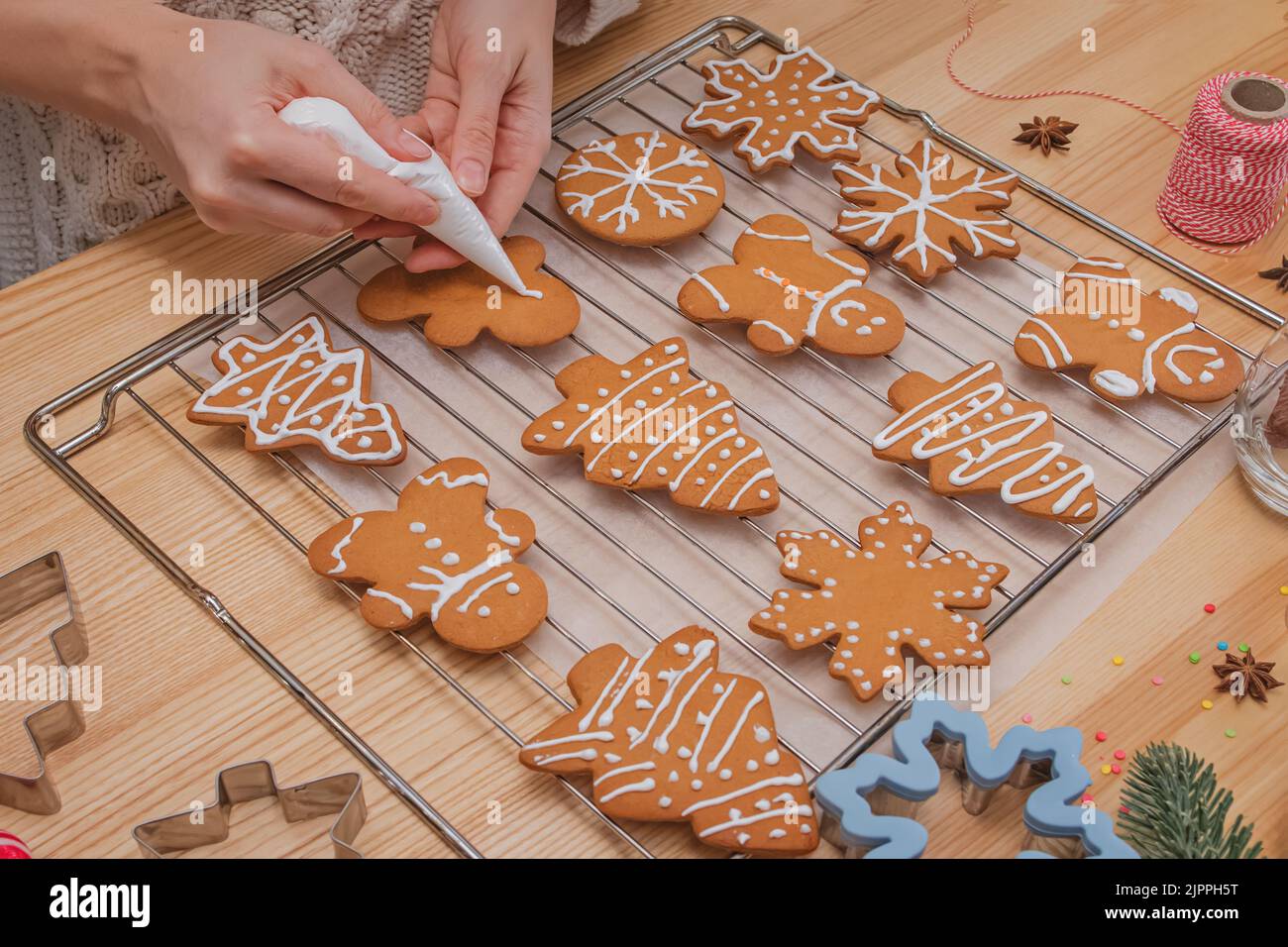 Mani della donna che decorano i biscotti fatti in casa del pan di zenzero di Natale, vista dall'alto Foto Stock