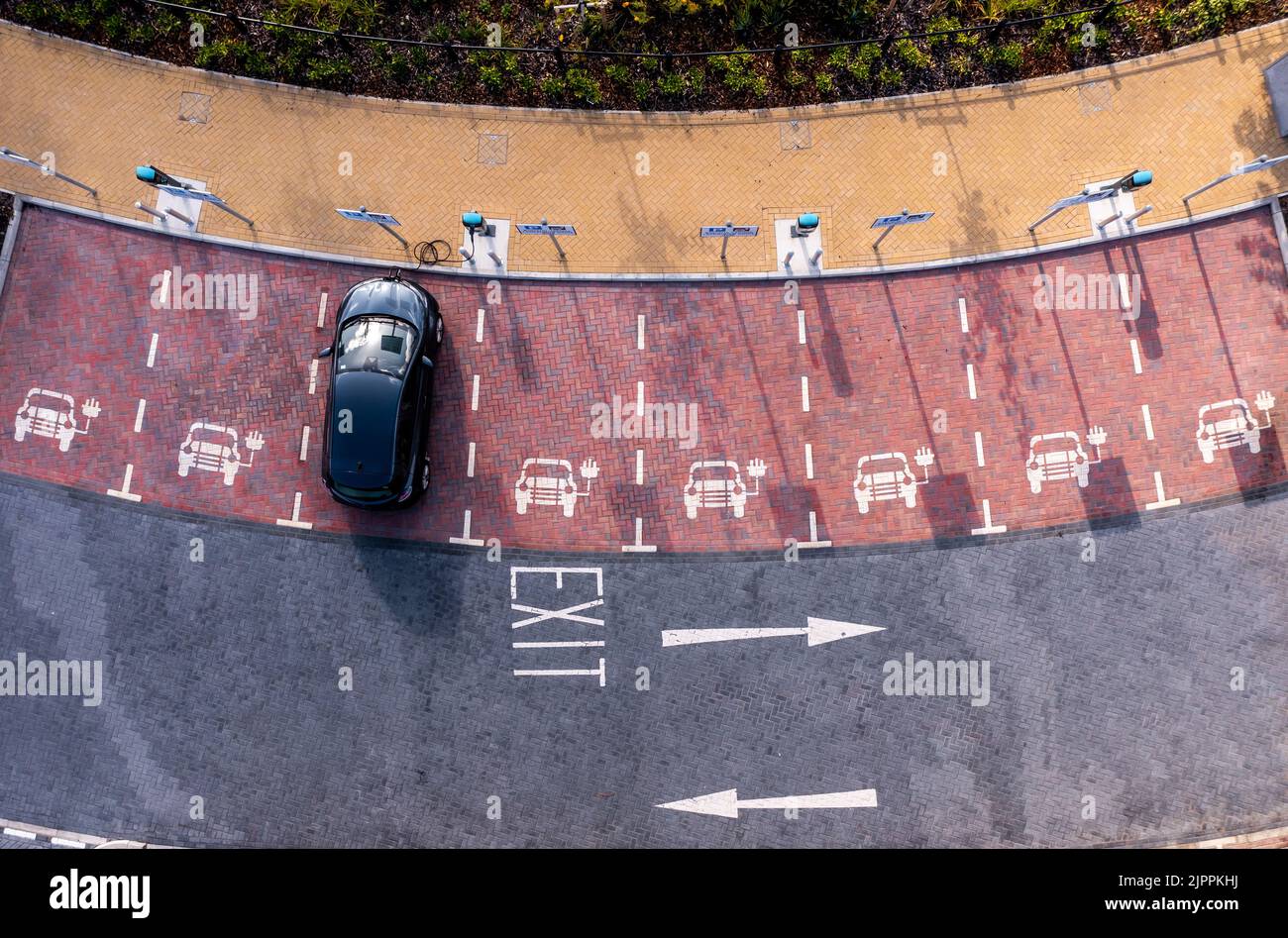 Una vista aerea direttamente sopra una stazione di ricarica di un veicolo elettrico con ricarica di un'auto elettrica in un parcheggio Foto Stock