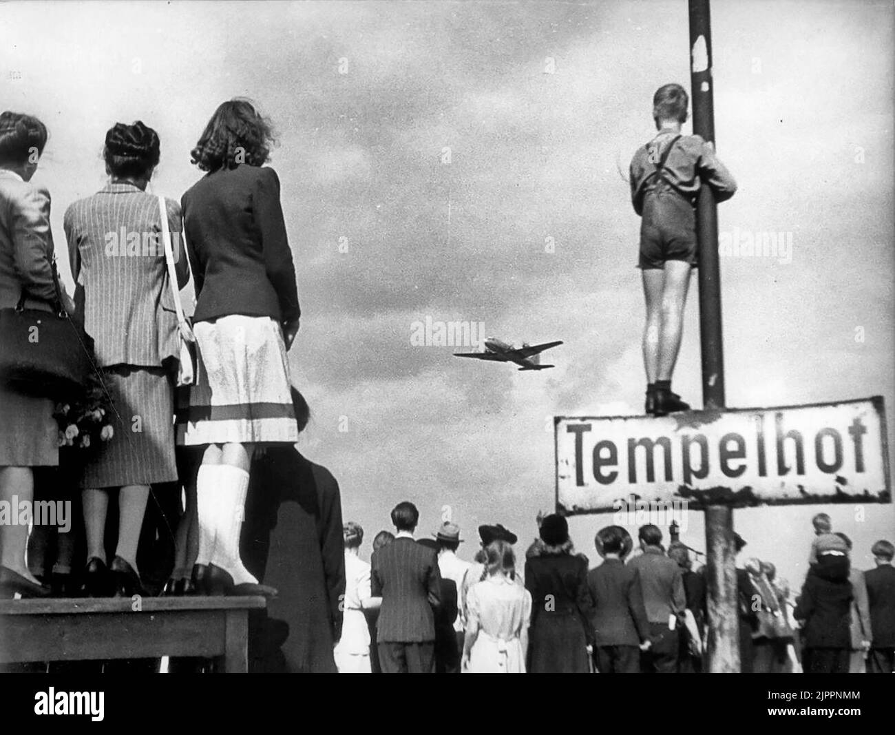 I civili che osservano un aereo atterrano durante il blocco di Berlino, 1948 Foto Stock