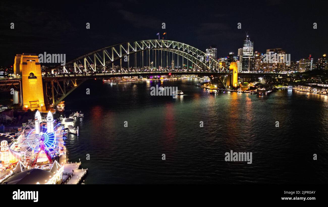 Una vista aerea del Sydney Harbor Bridge a Sydney, Australia, con luci vibranti riflesse nell'acqua di notte Foto Stock