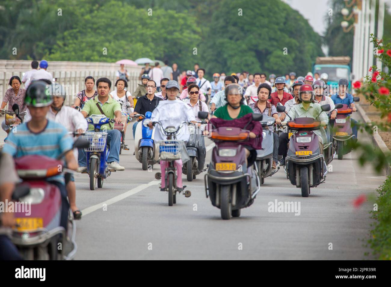 Persone il pendolarismo nelle prime ore del mattino su biciclette e scooter in una corsia separata nella città di Nanning, Guangxi, a sud ovest della Cina. Foto Stock