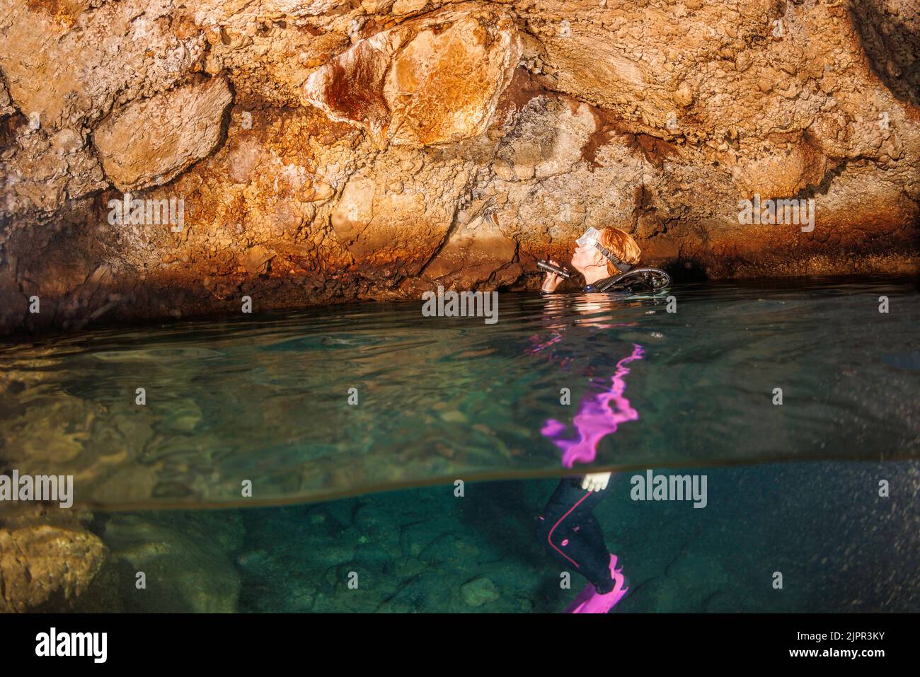 Una scena divisa di un subacqueo (MR) raffigurato in una caverna di lava che ha un'apertura verso una camera d'aria all'interno dell'isola di Maui, Hawaii. Foto Stock
