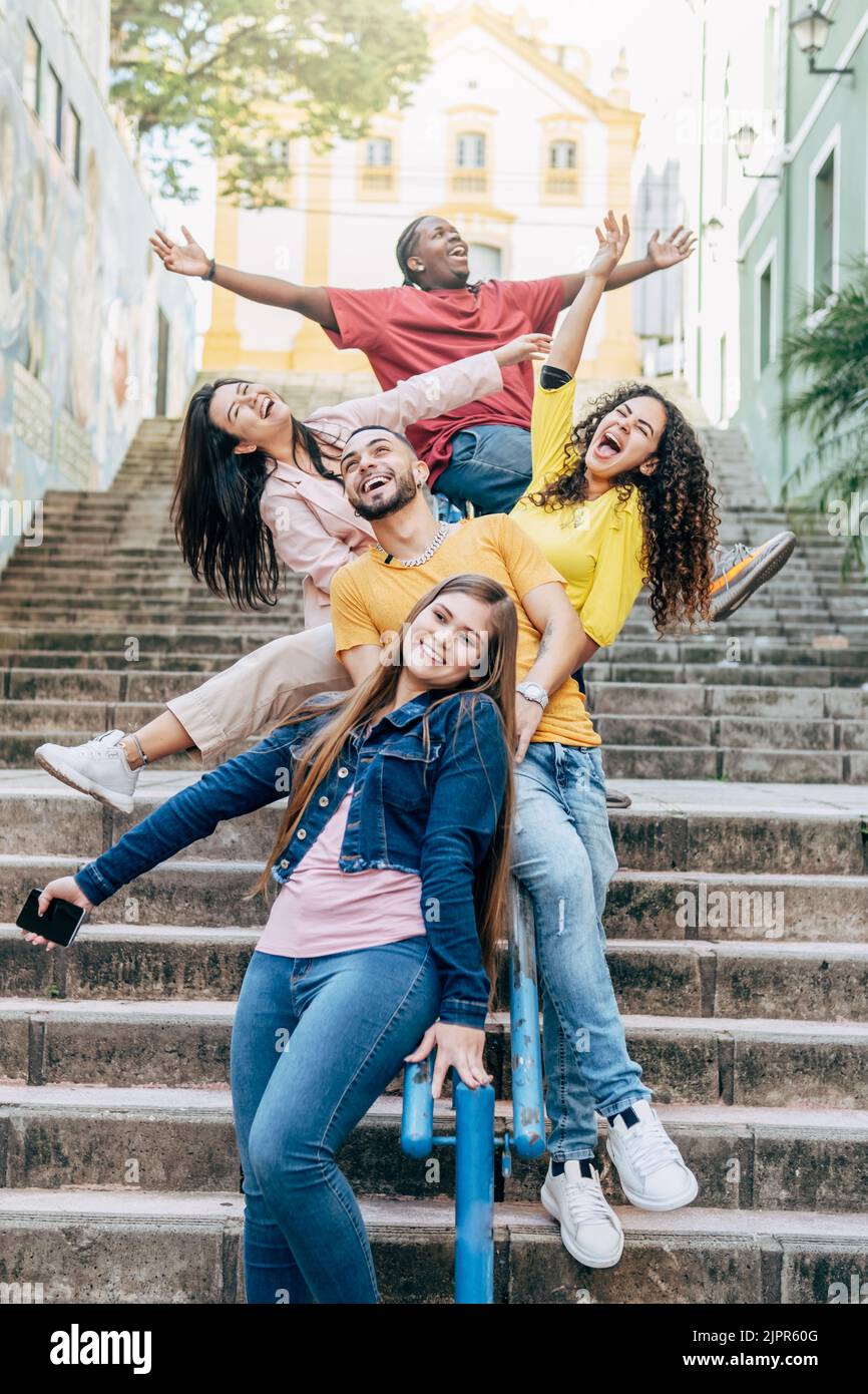 Gruppo di giovani amici felici e diversi che si divertono insieme nelle strade della città con le braccia alzate - concetto di amicizia Foto Stock