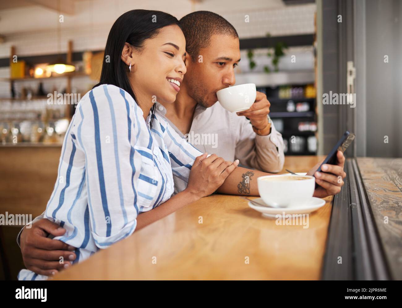 Coppia che utilizza i social media su un telefono e beve il tè in una caffetteria insieme. Felice uomo e donna con 5g smartphone per inviare SMS e cercare Foto Stock