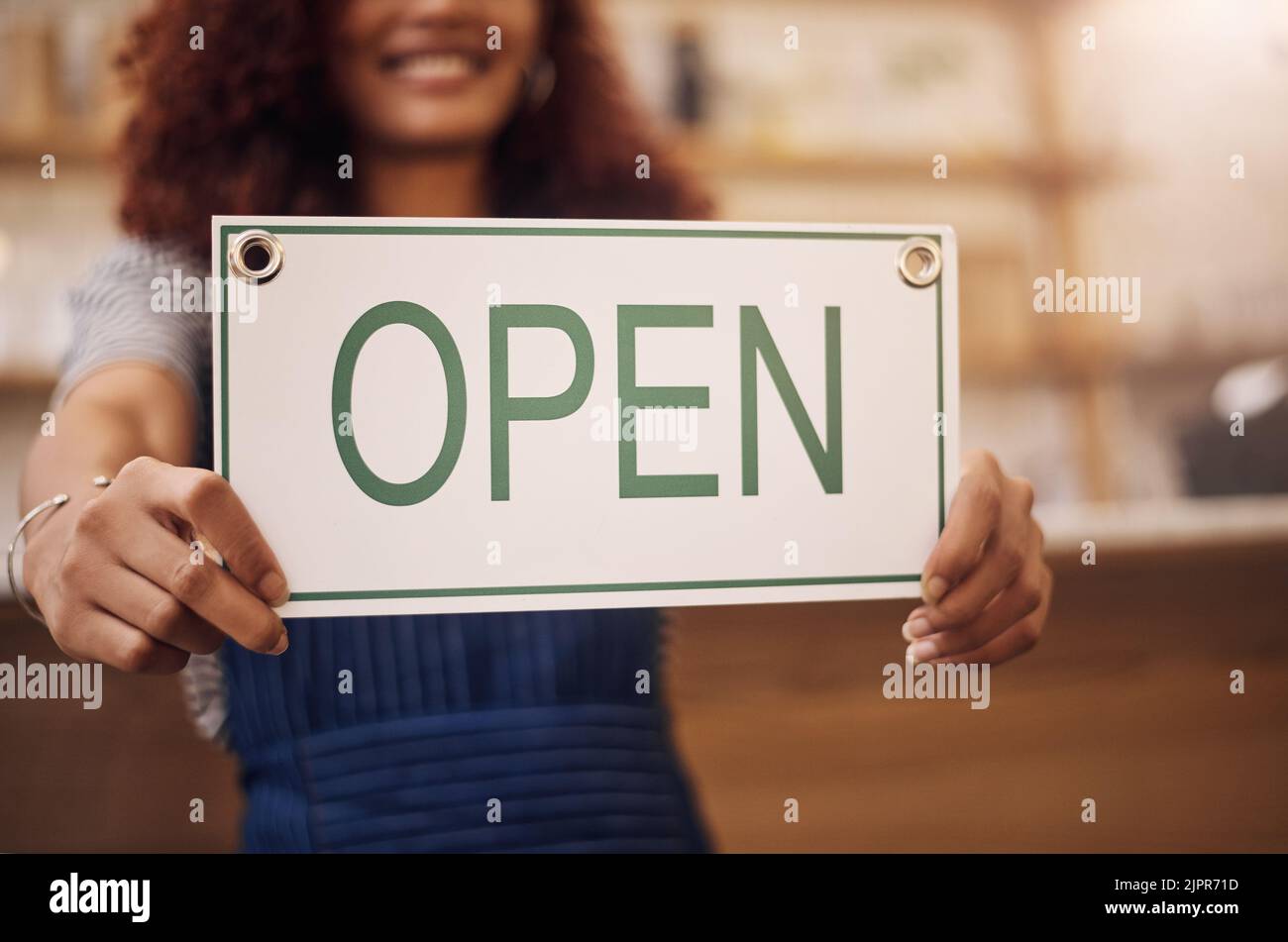 Non vediamo l'ora di darti il benvenuto. Primo piano di una donna che tiene in mano un cartello aperto nel suo negozio. Foto Stock