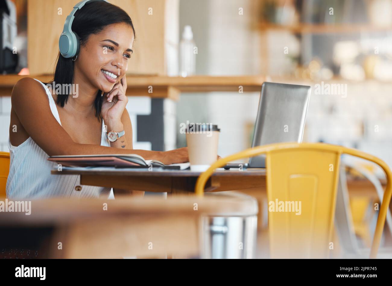 Donna creativa nel bar con cuffie che ascoltano musica, guardano i social media online sul laptop o pianificano una strategia seo digitale. Remoto Foto Stock