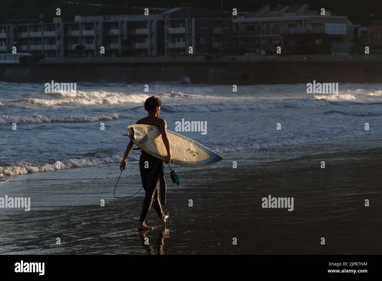 Un surfista sulla spiaggia di Kamakura. Kanagawa, Giappone. Foto Stock