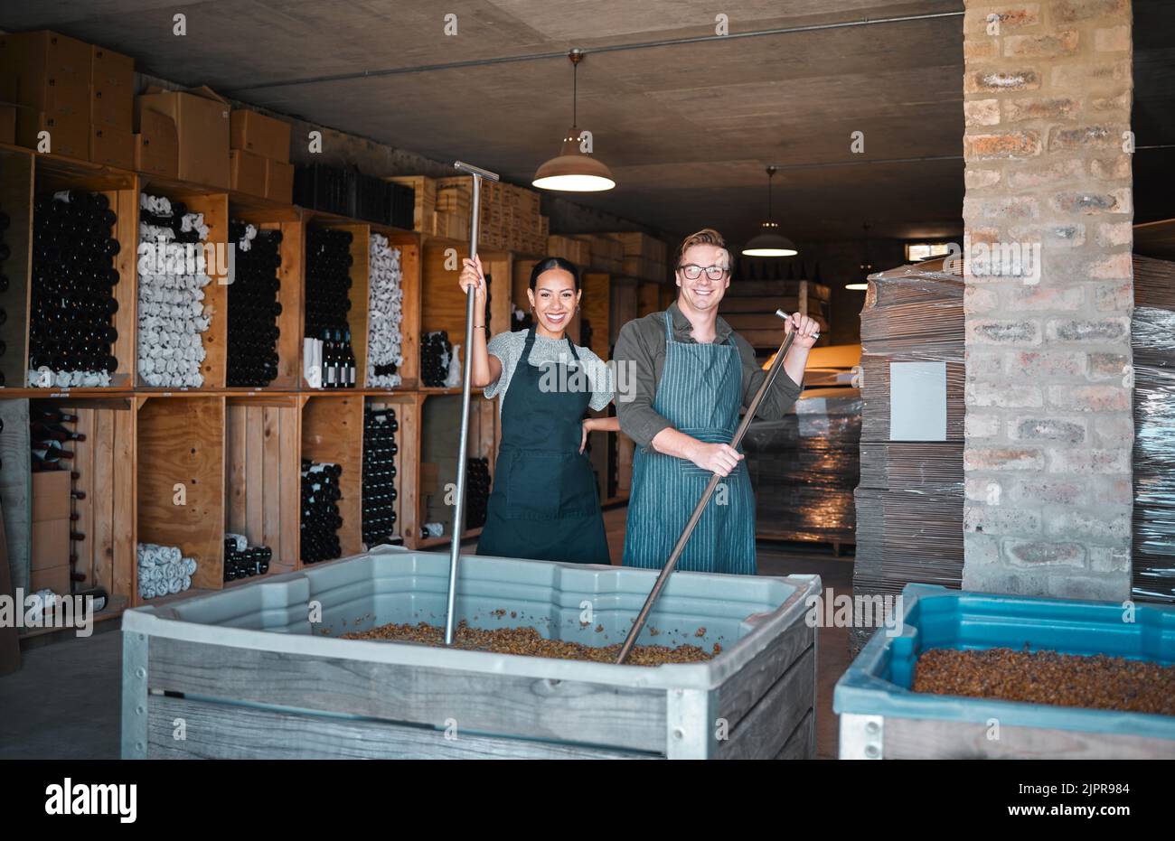 Vinificazione, produzione e cantina lavoratori frantumano, mescolano e mescolano serbatoio aperto per il processo di alcol. Ritratto di personale felice in fabbrica e l'industria vinicola Foto Stock