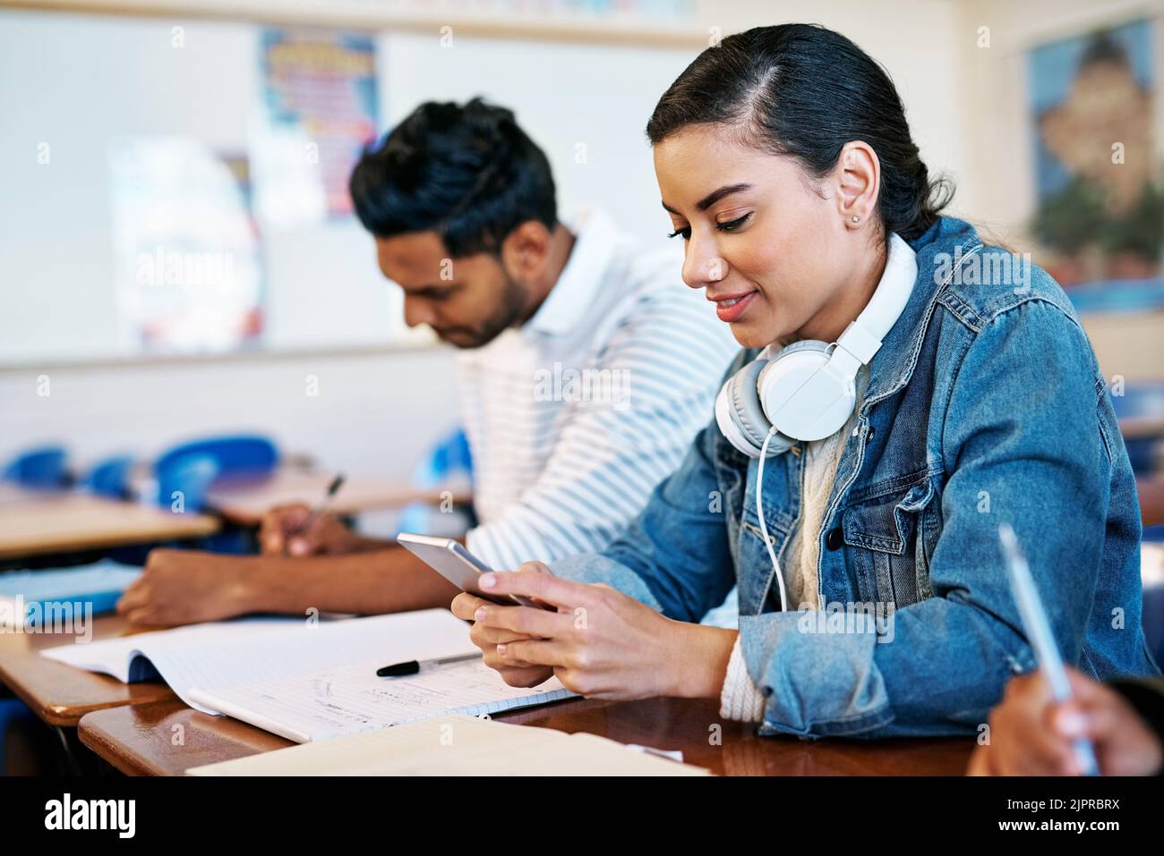 Alcuni testi meritano la distrazione: Un giovane studente universitario allettante che invia un messaggio di testo mentre si siede in classe. Foto Stock