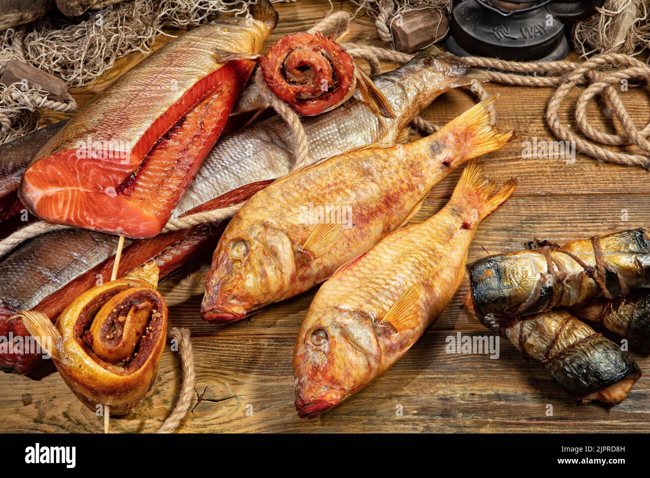 Diversi tipi di pesce affumicato e fushing net su una scrivania in legno Foto Stock