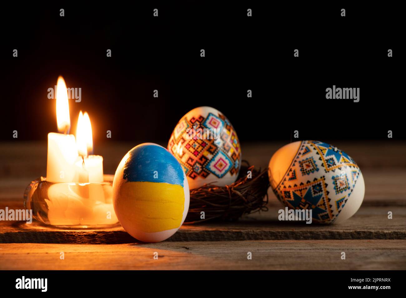 Colorante uovo di pollo con una bandiera dipinta di Ucraina e una fiamma di candela sul tavolo a casa in Ucraina al buio, vacanze di Pasqua in Ucraina durante la wa Foto Stock