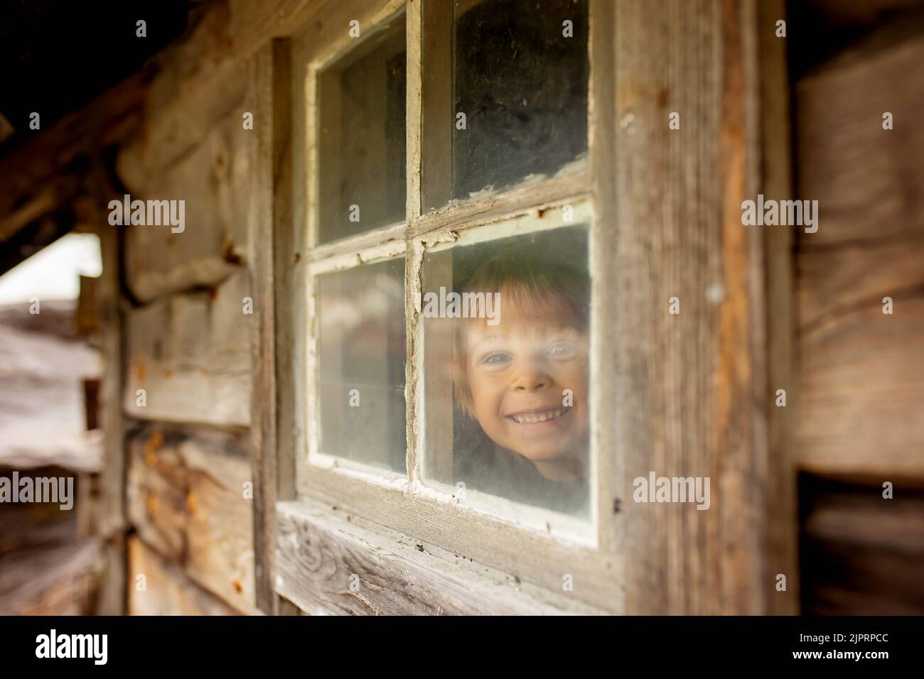 Piccola casa in legno, splendida accanto a una cascata sul molo di Hellesylt, bambino che gioca in casa, guardando fuori dalla finestra Foto Stock