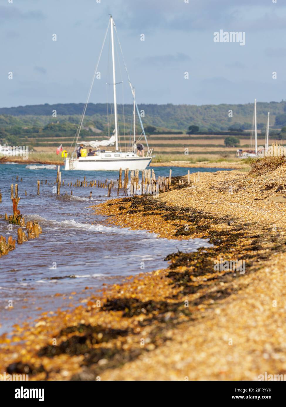 Agosto 2022, Isola di Wight, Regno Unito. Uno yacht si insena nell'idilliaco porto di Newtown Creek sul solent. Vista lungo la spiaggia fino all'ingresso del porto. Foto Stock
