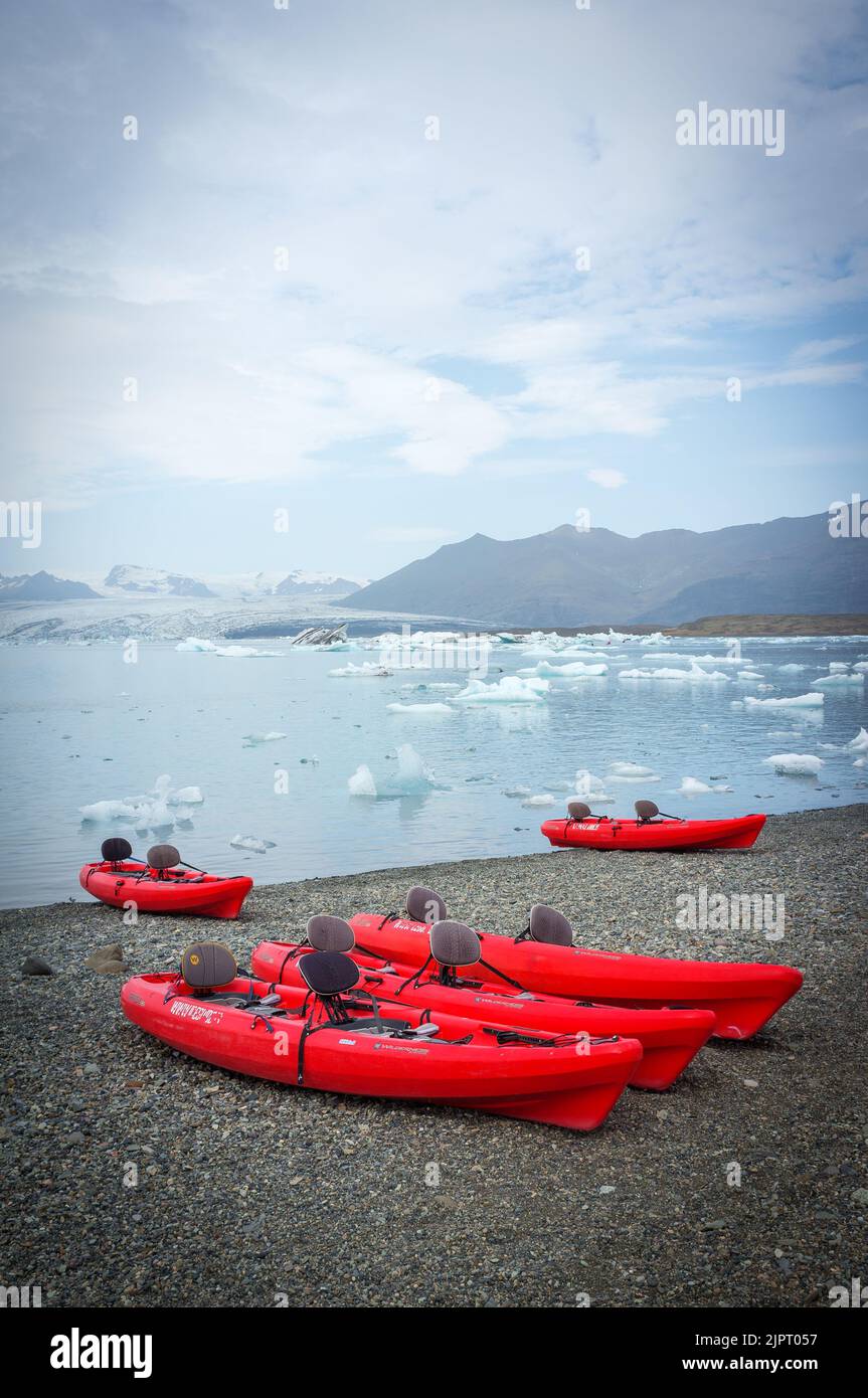 Uno scatto verticale della Laguna di Ghiacciaio con iceberg e canoe rosse a Row, Jokulsarlon, Islanda Foto Stock