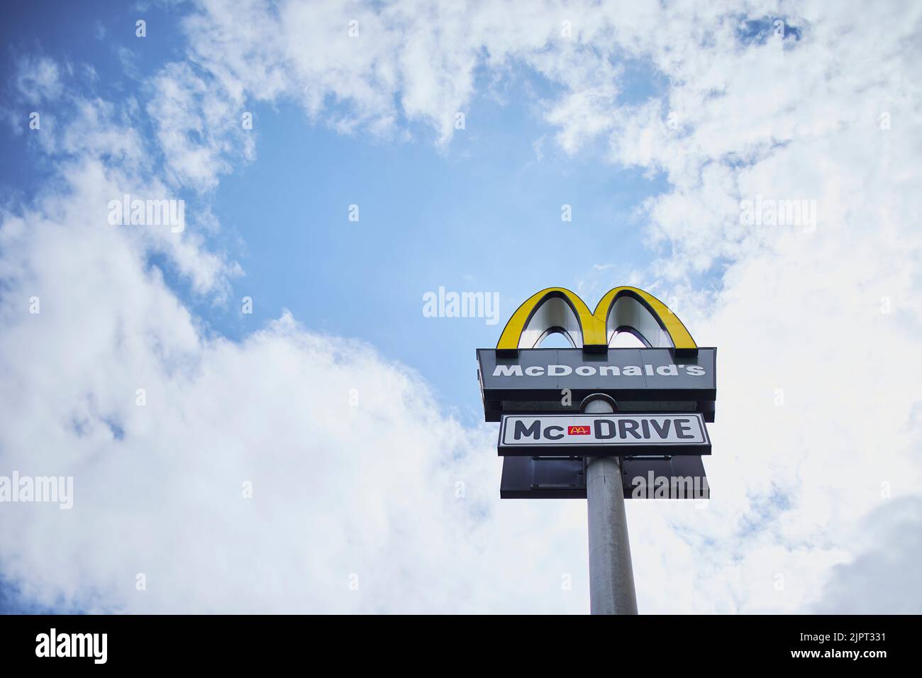 Un'inquadratura a basso angolo del logo di un fast food sotto un cielo nuvoloso blu Foto Stock