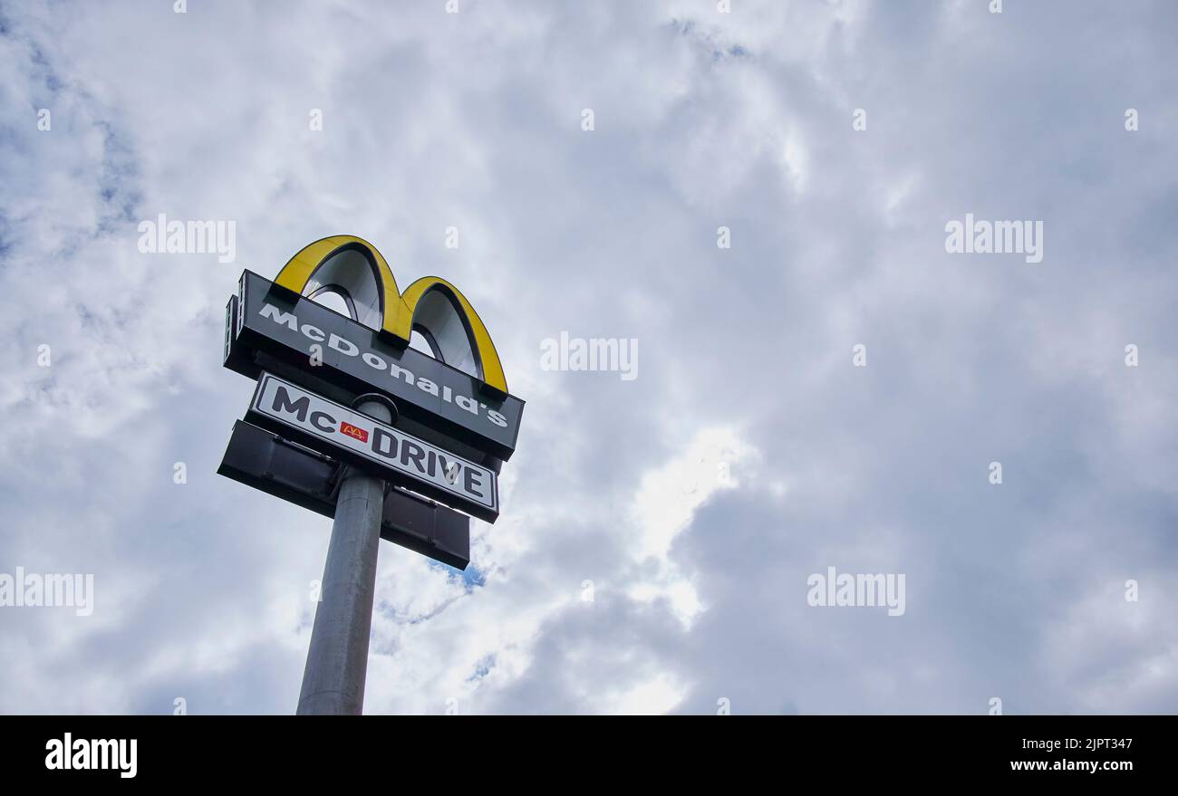 Un'inquadratura a basso angolo del logo di un fast food sotto un cielo nuvoloso blu Foto Stock