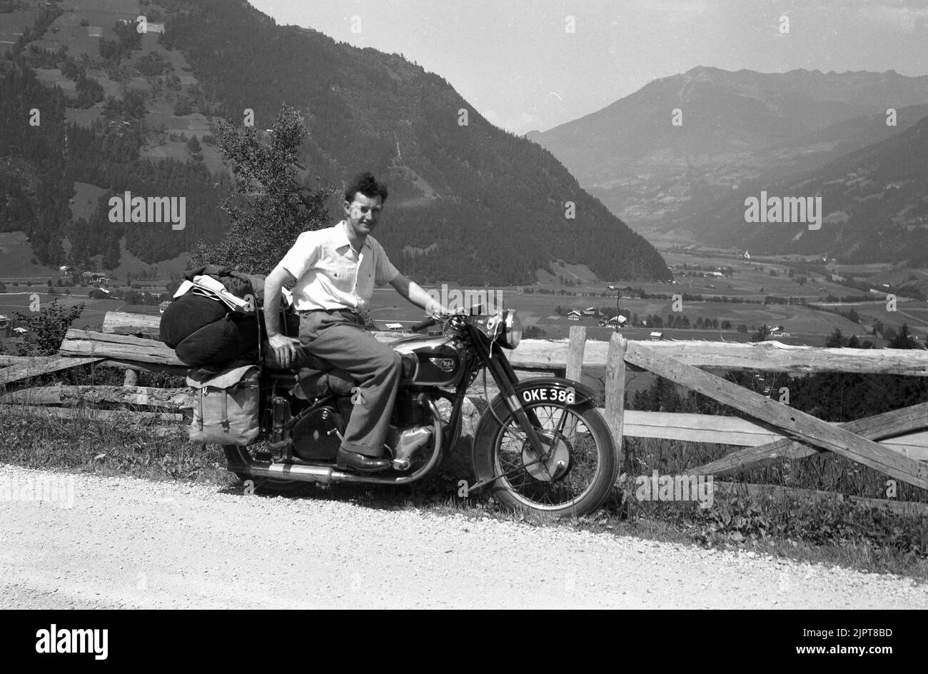 1950s, storico, su una strada di ghiaia di montagna, in una vacanza in giro per l'Europa, un giovane seduto su una moto BSA dell'epoca, bagagli e panniere in tela sul retro della moto. Foto Stock