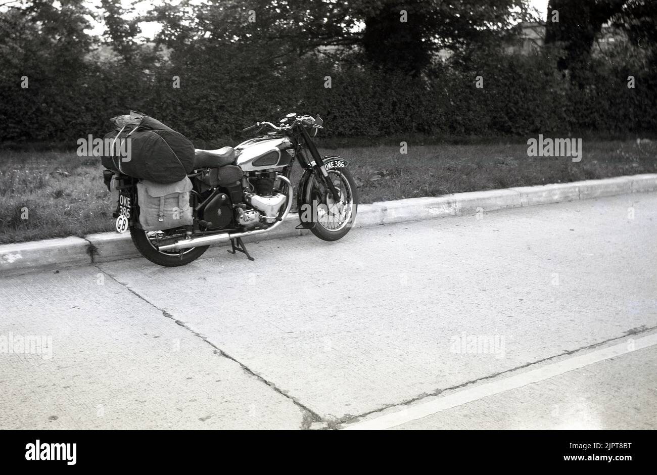 1950s, storico, parcheggiato su una strada, una moto BSA dell'epoca. Sul retro della moto, una custodia in stoffa impaccata sulle mutandine in tela pronta per una vacanza in giro per l'Europa. Foto Stock