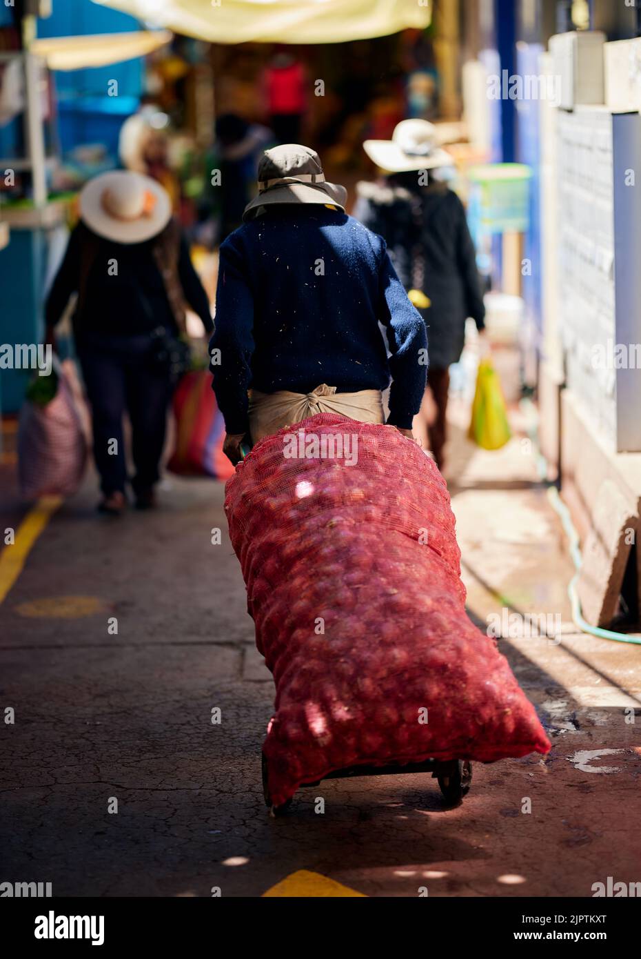 Un colpo verticale di una persona che trasporta un sacchetto pesante di verdure ad un mercato di strada in Perù Foto Stock