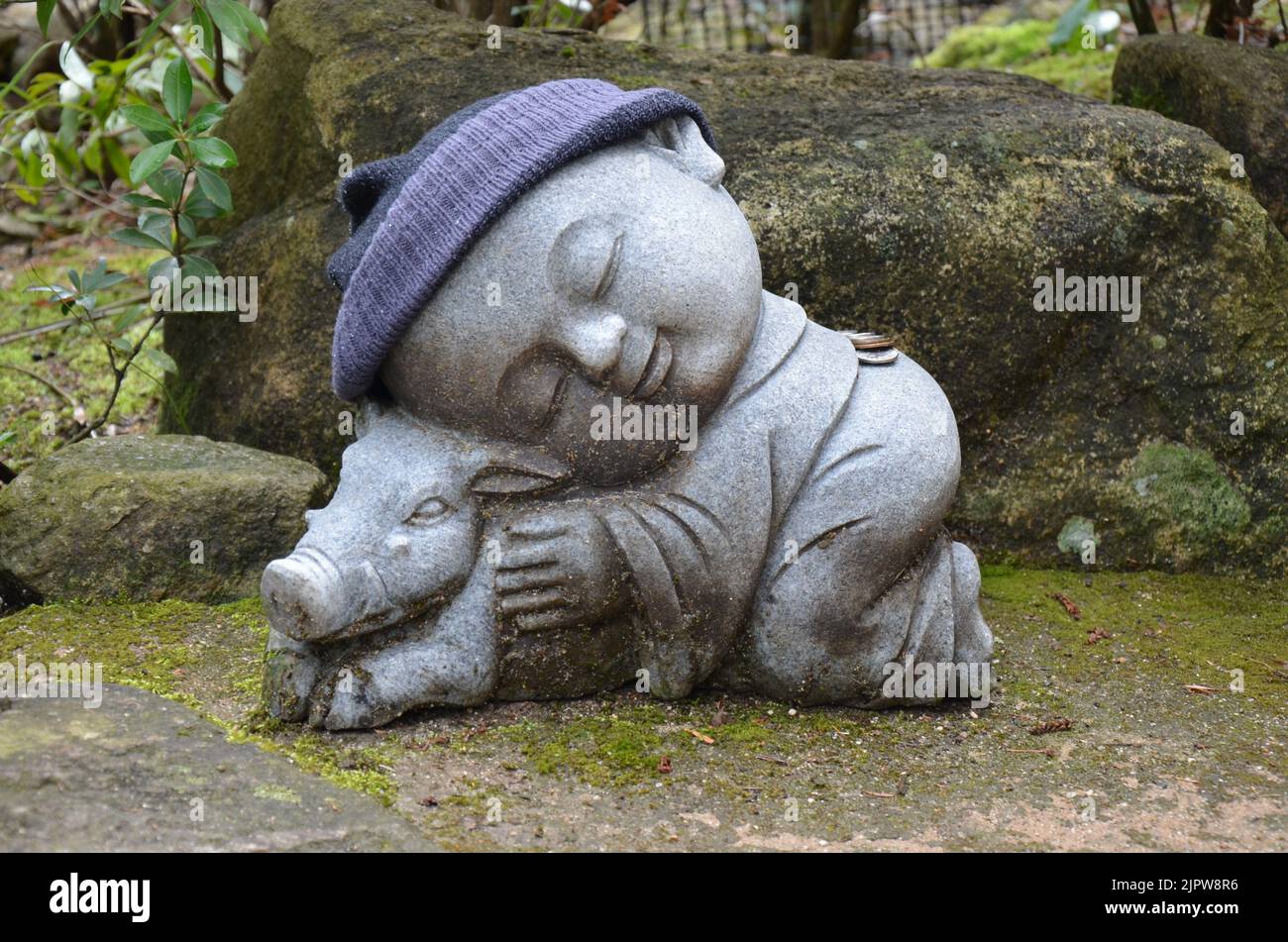 Jizo Bosatsu, statua del monaco buddista con un maiale. Tempio di Daishoin, isola di Miyajima, Giappone Foto Stock