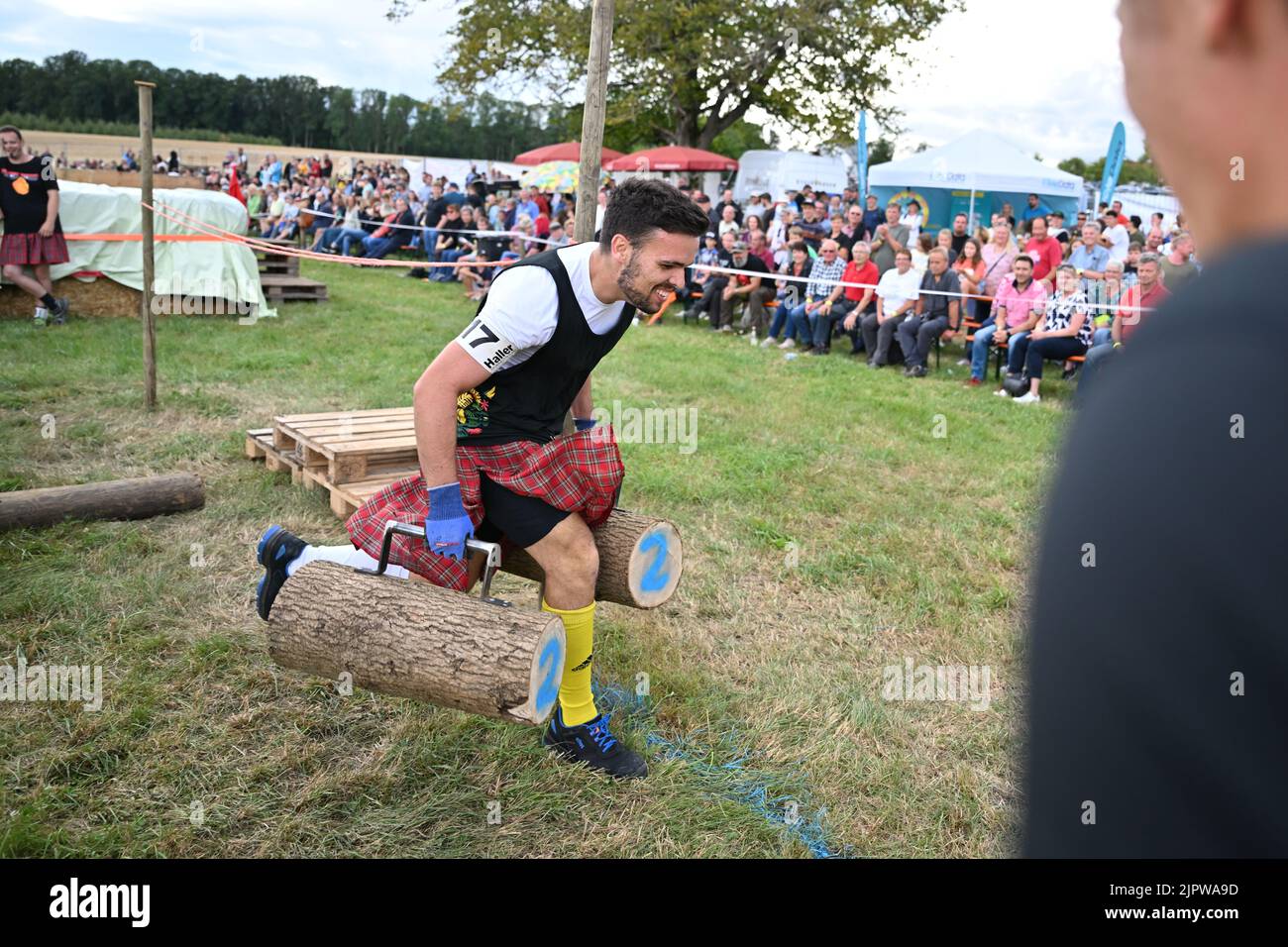 Wilhelmskirch, Germania. 20th ago, 2022. Justin Gühring corre attraverso un corso con due tronchi d'albero nelle sue mani al 'Oberschwäbische Highländgames'. Squadre provenienti da tutta la Germania meridionale si sono incontrate per competere nei giochi. Credit: Felix Kästle/dpa/Alamy Live News Foto Stock