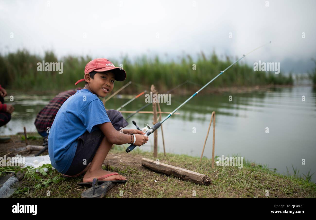 UBUD, BALI, INDONESIA, 15 MAGGIO 2017; Ritratto di ragazzo e suo padre pesca da Beratan lago. Immagine indonesiana del ragazzo. Foto Stock