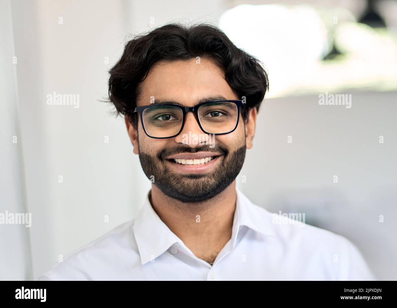 Giovane uomo d'affari indiano sorridente che indossa occhiali, ritratto alla testa. Foto Stock