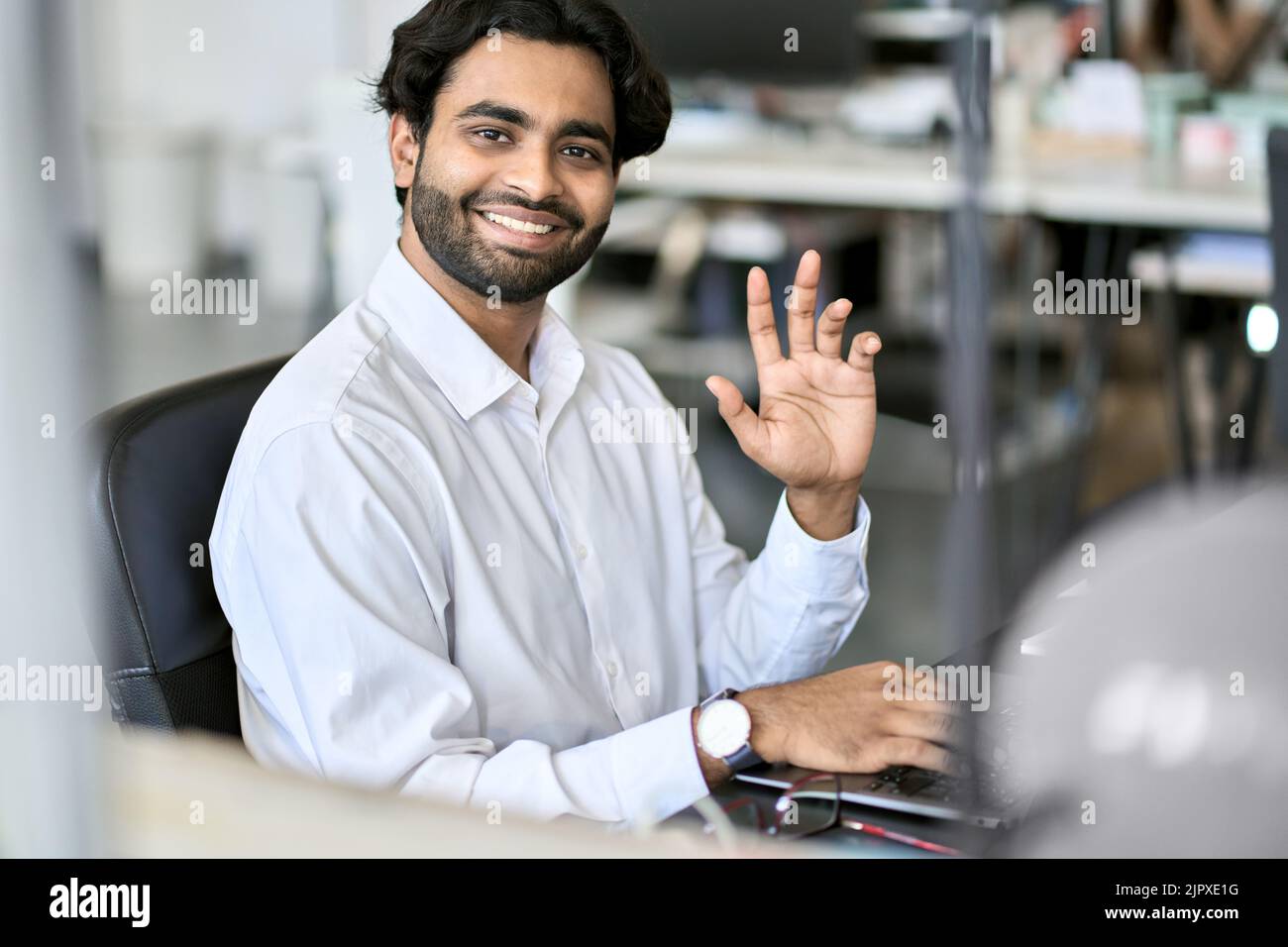 Felice dipendente di un'azienda indiana giovane che lavora su un notebook. Verticale Foto Stock