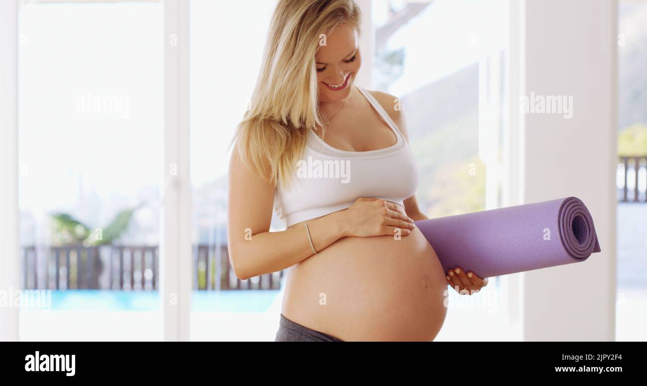 Fate bene dentro là. Una giovane donna incinta attraente che trasporta un tappetino di yoga. Foto Stock