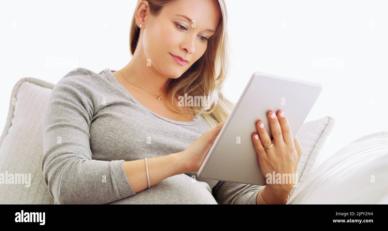 Può fare tutto dalla comodità della sua casa. Una donna incinta che usa un tablet a casa. Foto Stock