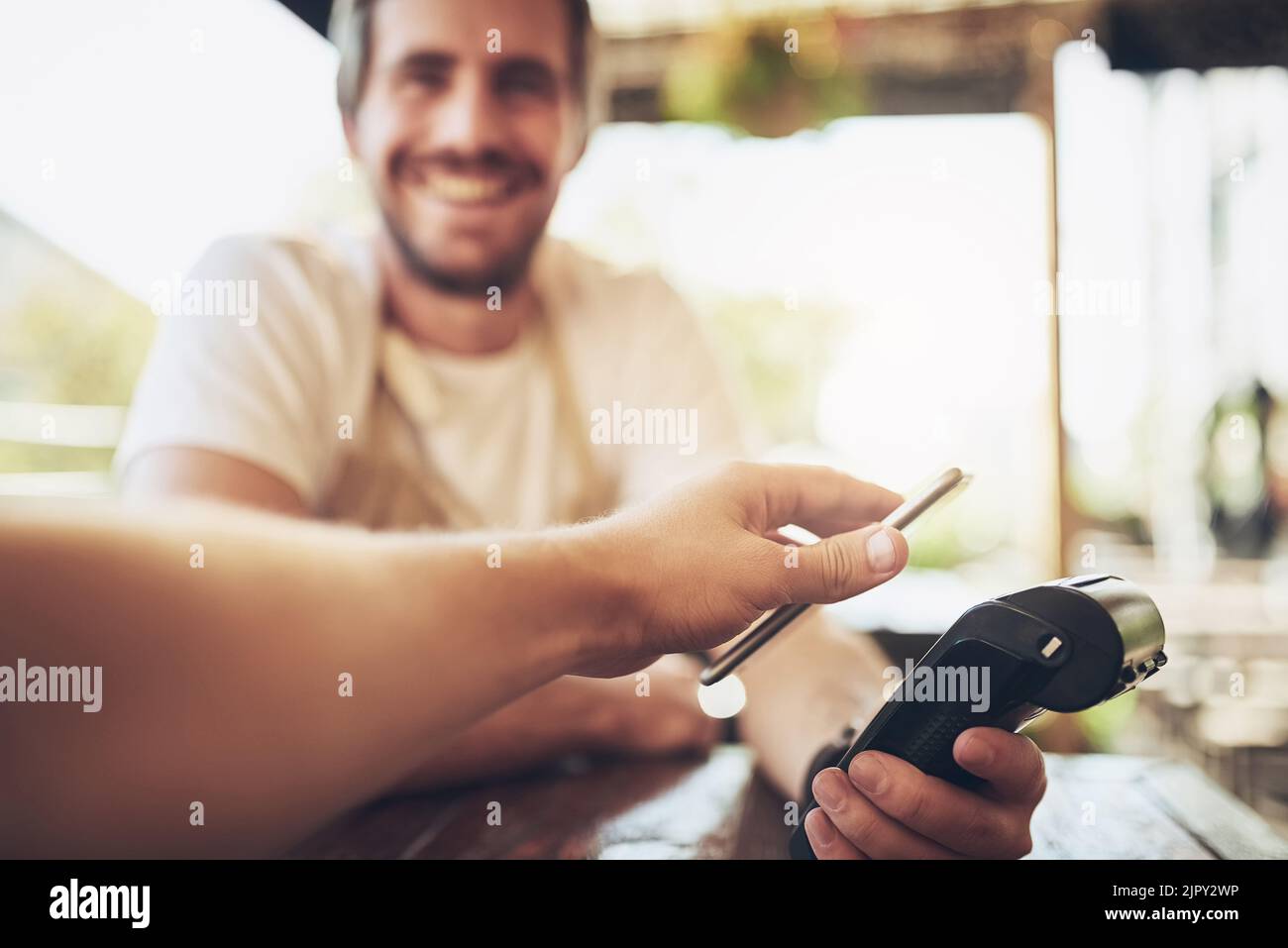 Il modo più semplice e sicuro per pagare il caffè. Un uomo che effettua il pagamento wireless in un bar. Foto Stock