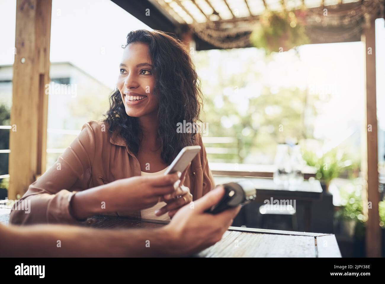 Non ho bisogno di una borsa solo il mio telefono. Una donna che effettua un pagamento wireless in una caffetteria. Foto Stock