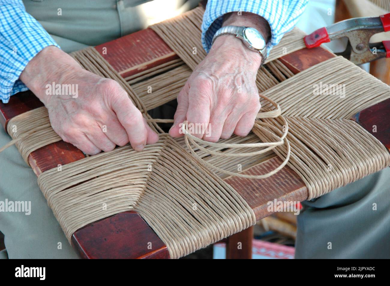 Le mani che lavorano ad una mostra di arte e artigianato facendo artigianato e tessitura d'arte per la vendita Foto Stock