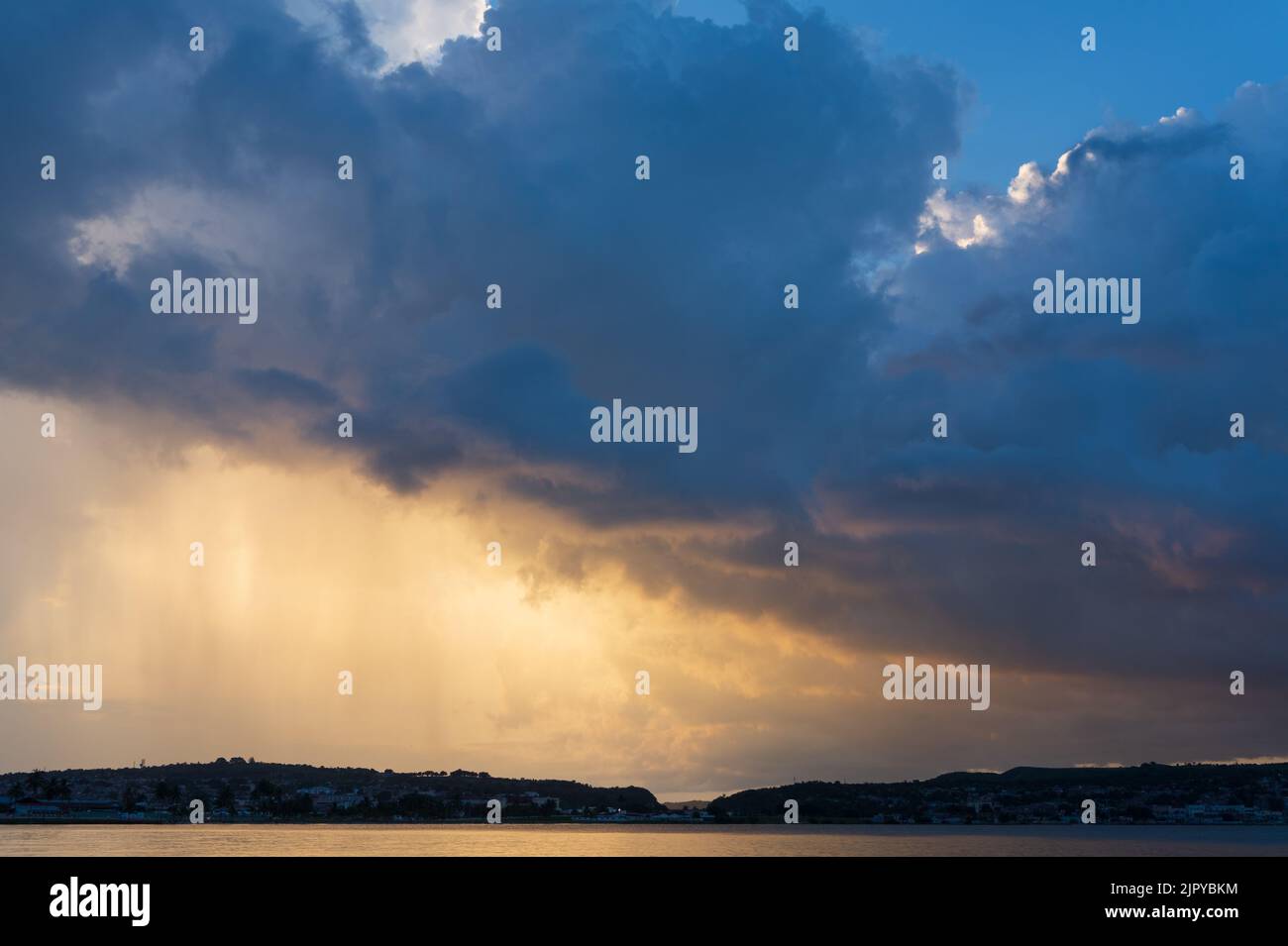 Tramonto nella baia di Matanzas in estate con il sole riflesso nell'acqua e le rocce in primo piano. Foto Stock