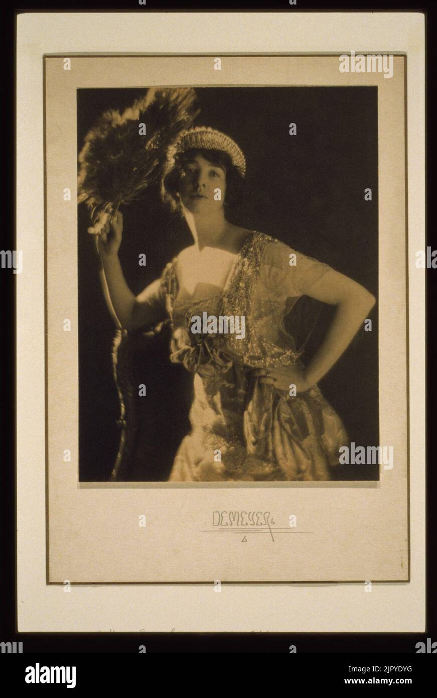 Ritratto di Gertrude Vanderbilt Whitney di tre quarti (Sig.ra. Harry Payne Whitney) indossando un abito gioiellato e una tiara e tenendo un fan di piume di pavone) - De Meyer Foto Stock