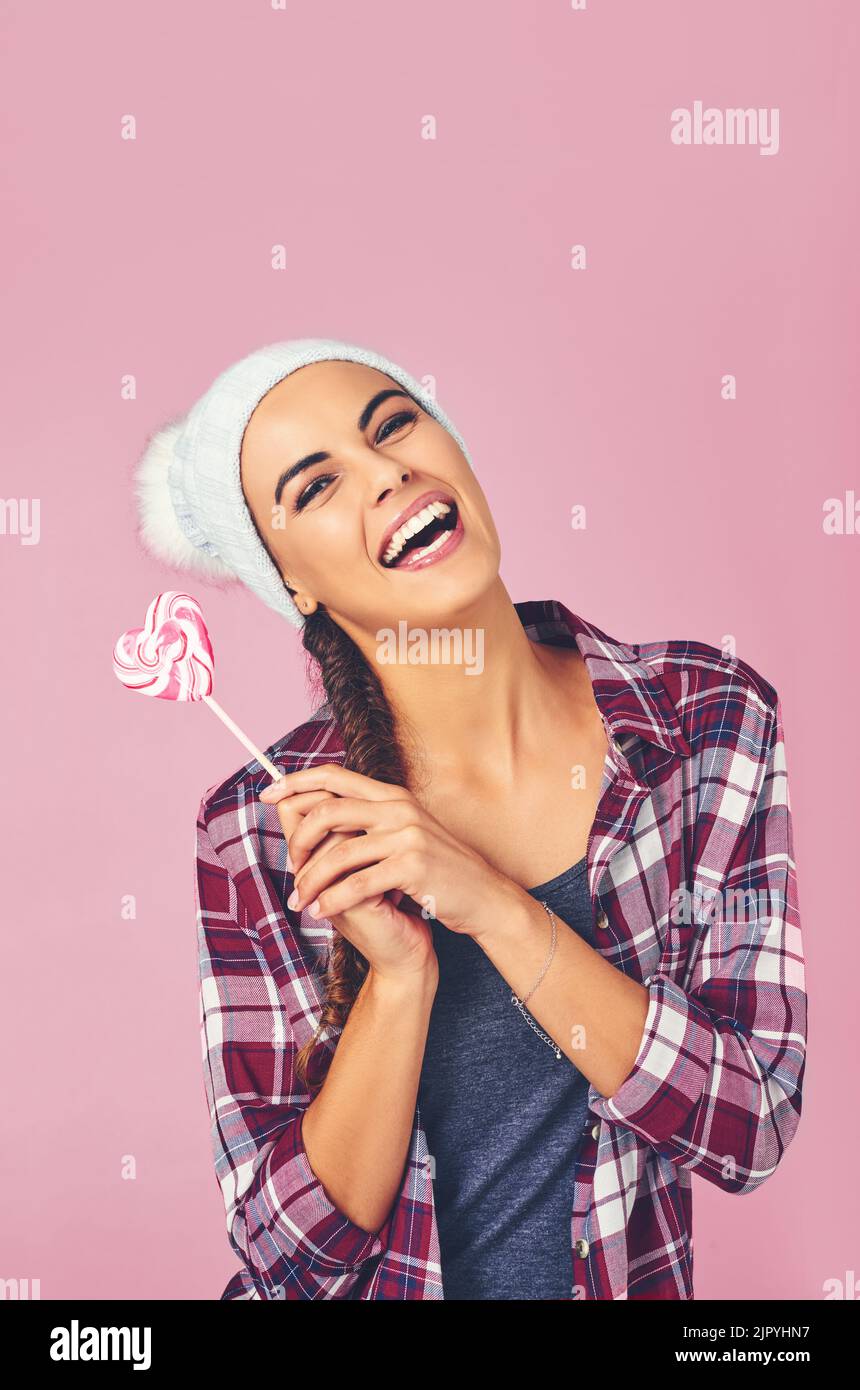 Im appena una ventosa per le cose dolci. Una giovane donna che tiene un lollipop a forma di cuore su uno sfondo colorato. Foto Stock