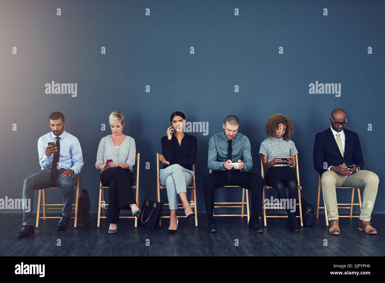 Qualcuno sta per essere assunto. Studio di un gruppo di uomini d'affari che utilizzano dispositivi wireless mentre sono in attesa in linea. Foto Stock