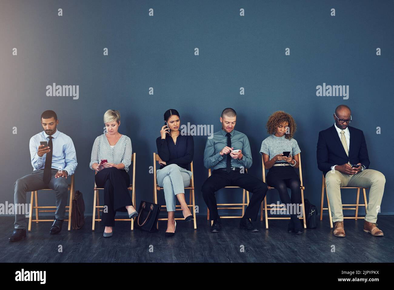 Era tempo di un cambiamento di carriera. Studio di un gruppo di uomini d'affari che utilizzano dispositivi wireless mentre sono in attesa in linea. Foto Stock