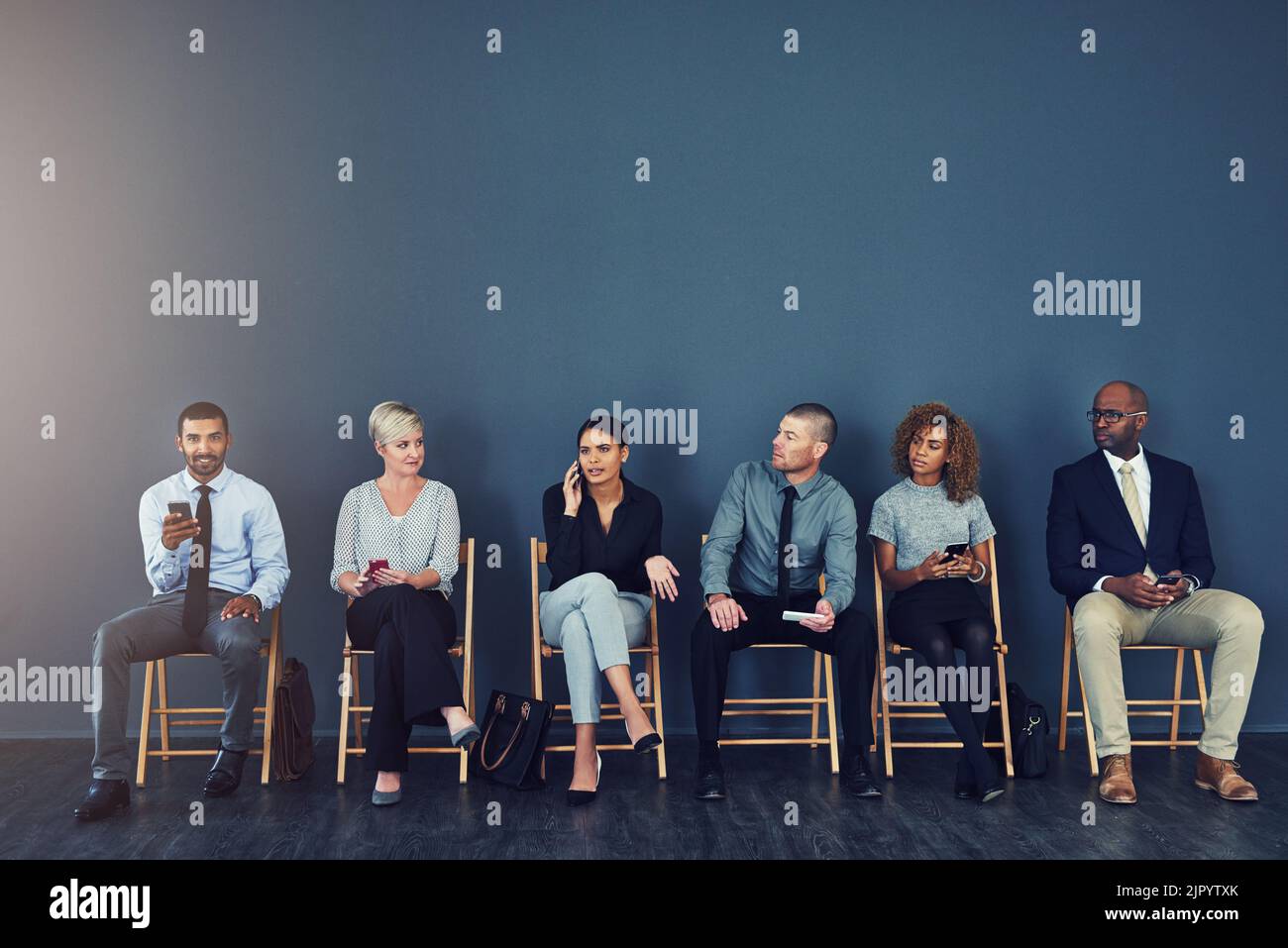 Avanti in linea per un nuovo lavoro. Studio di un gruppo di uomini d'affari che utilizzano dispositivi wireless mentre sono in attesa in linea. Foto Stock