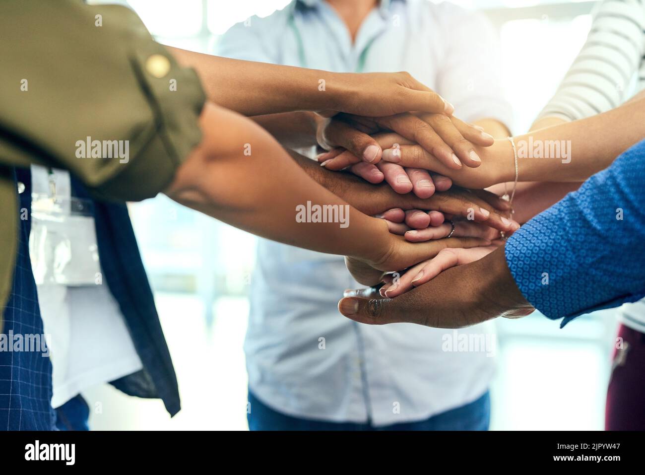 Heres alla nostra amicizia. Un gruppo di persone irriconoscibili mettendo le mani insieme in una huddle in un lato di un edificio. Foto Stock